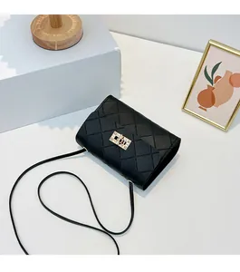 Detail of black quilted crossbody bag featuring a golden metal lock and PU leather texture