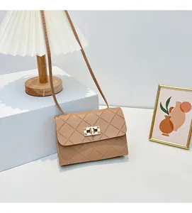 Detail of quilted texture and gold metal twist lock on a beige crossbody bag