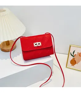 Detail of red quilted crossbody bag with metal twist lock on a white geometric stand