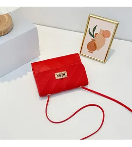 Detailed view of the bright red quilted crossbody bag with a gold twist lock and strap