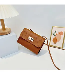 Detail of caramel quilted crossbody bag featuring a golden twist lock on white background