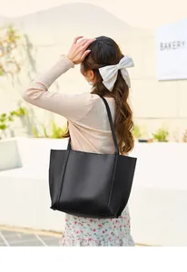 Détail d'un grand sac cabas noir porté à l'épaule dans un décor extérieur urbain