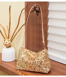 Close-up of golden sequin shoulder bag with detailed metallic texture and thin strap