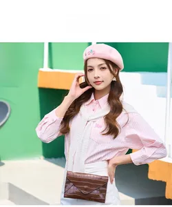 Detail of pink knit beret and brown crocodile pattern crossbody bag on a female model