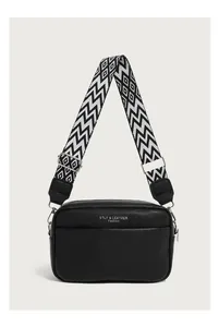 Close-up of black lychee grain leather bag with a stylish geometric woven shoulder strap