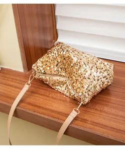 Detail of a sparkling gold sequin handbag with a zipper closure and beige strap