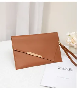 Detail der braunen Umschlag-Clutch mit schräger Klappe und goldener Verzierung