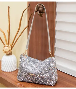 Detail of silver sequin shoulder bag with golden hardware on a wooden surface