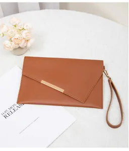 Nahaufnahme der braunen Briefumschlag-Clutch mit asymmetrischer Klappe und Goldbesatz