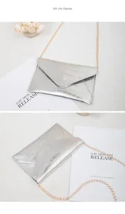 Detail of silver crocodile-textured envelope bag with a thin gold chain strap
