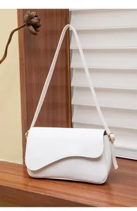 Dettaglio della patta a onde e finiture dorate sulla borsa bianca in ecopelle