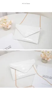 Close-up of white crocodile pattern texture and gold chain on small envelope bag