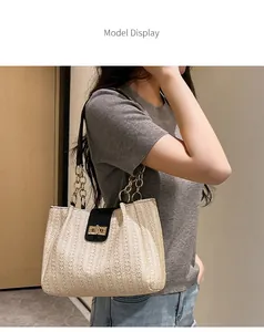Detail of woven cream shoulder bag with black leather flap and golden chain strap