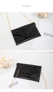 Detail of black crocodile texture envelope bag with elegant golden chain strap