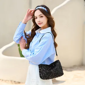 Fashionable black sequin shoulder bag with leather strap on a model outdoors