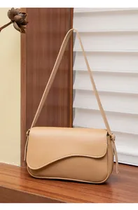 Dettaglio borsa a tracolla beige con patta ondulata elegante e fibbie in metallo dorato