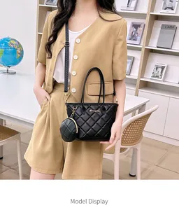 Primer plano del bolso tote acolchado negro con logo dorado y monedero redondo a juego