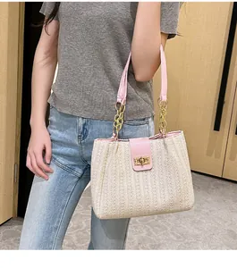 Detail of woven tote bag showing beige texture and pink strap with gold chain