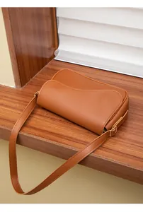 Dettaglio della borsa a tracolla marrone caramello con patta ondulata e pelle sintetica