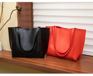 Détail de grands sacs cabas en similicuir noir et orange posés sur une étagère