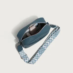 Blue litchi grain crossbody bag with geometric wide strap and internal storage view