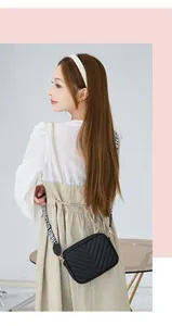 Detail of black quilted crossbody bag with embroidered V-pattern and wide fashion strap
