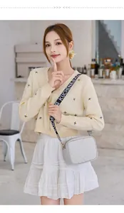 Detail of light gray crossbody bag with V-shaped quilting and logo webbed strap