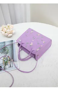 Detailed embroidery of pink flowers on a lavender mini tote bag with a purple strap