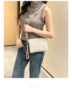 Sac bandoulière tissé beige porté par un mannequin avec bandoulière en cuir rose élégante