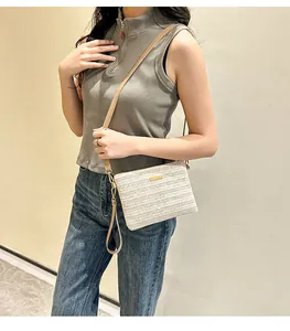 Détail d'un petit sac tissé crème avec plaque dorée et fine bandoulière en cuir