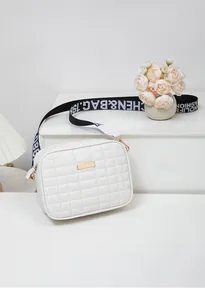 Close-up of white quilted crossbody bag with golden hardware and fashion letter strap