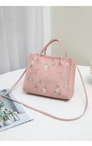 Close-up of floral embroidery on pink faux leather mini handbag with long strap
