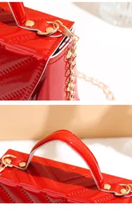 Detailed macro view of vibrant red patent leather with V-quilted stitching and gold hardware