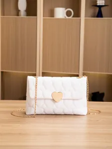 Detailed close-up of heart-shaped quilted pattern and gold heart buckle on white bag