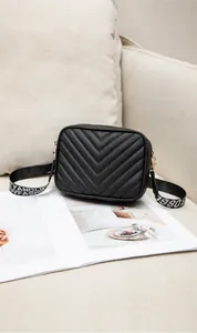 Detail der schwarzen Stepptasche mit V-Nähten und einem gemusterten Schultergurt