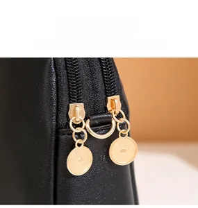 Macro detail of high-quality gold dual zippers on black embroidered crossbody bag