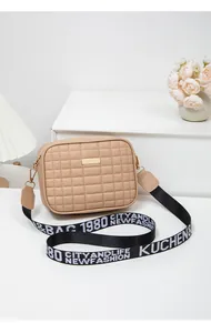 Close-up of khaki quilted crossbody bag with golden metal plaque and woven letter strap
