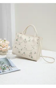 Close-up of pink flower embroidery on a cream handheld bag with high-quality stitching