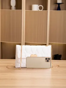 White quilted chain shoulder bag with heart lock compared to a smartphone for scale