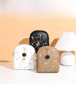 Detailed close-up of small crossbody bags with floral embroidery and cat charms