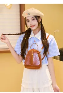 Détails de la texture en cuir marron brillant et du pendentif doré sur le mini sac à dos