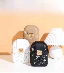 Detailed view of three embroidered small crossbody bags in white, khaki and black