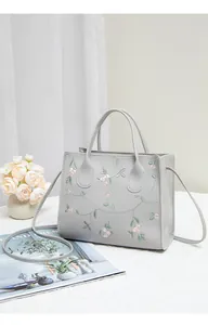 Detail of grey embroidered handbag with pink flower pattern and detachable strap