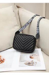 Detail of black quilted leather camera bag with embroidered wide nylon shoulder strap
