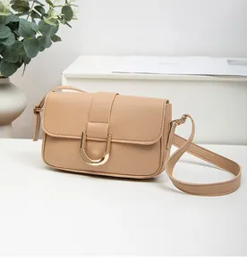 Close-up of beige crossbody bag with premium gold U-shaped metal buckle and smooth PU leather
