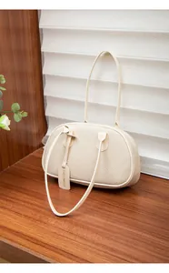 Detailaufnahme der beigen Handtasche aus PU-Leder mit Litschi-Struktur auf Holz