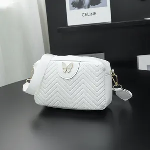 White quilted crossbody bag with decorative butterfly and wide textile shoulder strap