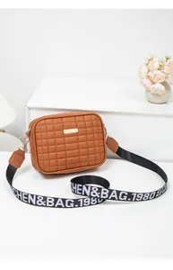 Detail of brown quilted crossbody bag with wide fabric strap and golden hardware