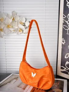 Detail einer orangefarbenen sichelförmigen Tasche mit weißem Schmetterlings-Ornament