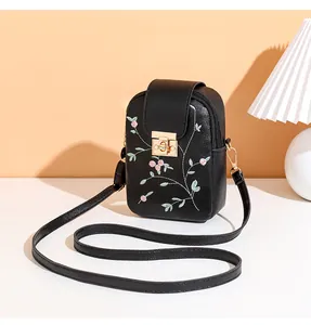 Close-up of floral embroidery and gold twist lock on black leather crossbody phone bag